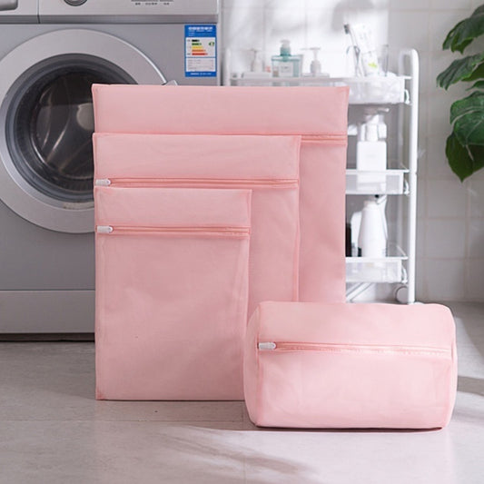 Set of pink laundry bags in front of a washing machine.